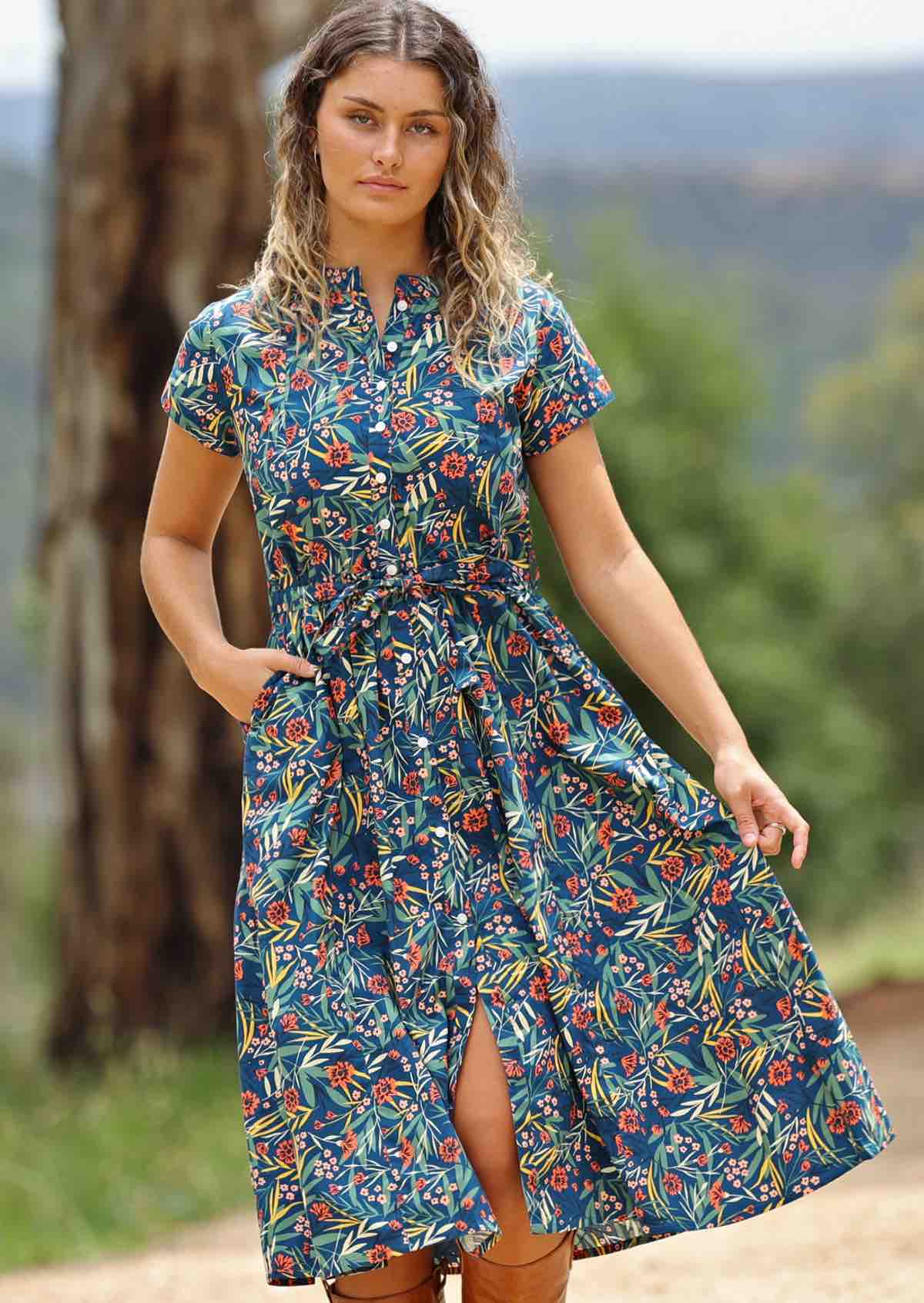 woman wearing floral button up retro style maxi dress trees and hills in background