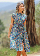 woman wearing floral button up retro style maxi trees and hills in background