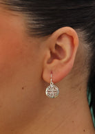 circular Celtic motif earrings on woman's ear