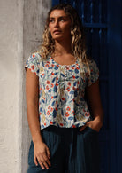 Model leans on wall in floral cotton top