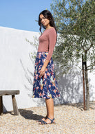 Woman wears floral printed cotton skirt with pockets, wide waistband and side zipper.