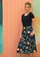 Women wears navy skirt with a green floral pattern. 