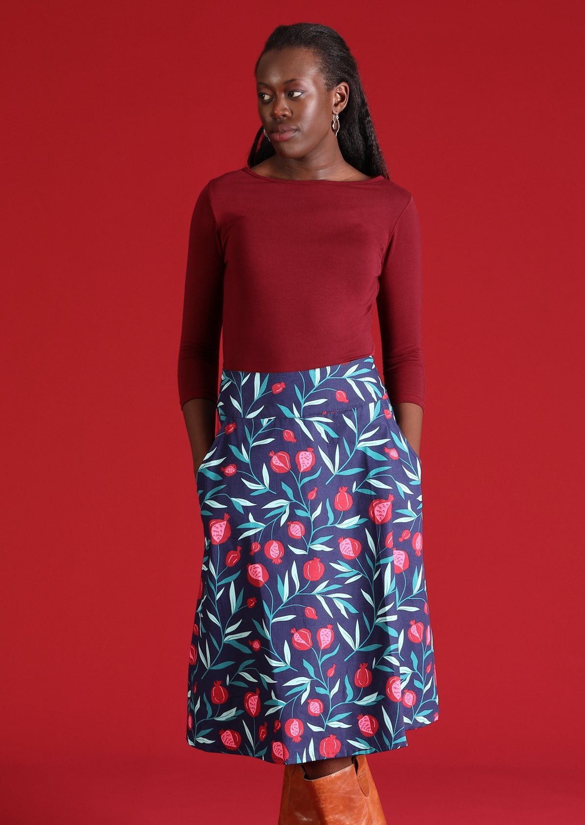 Model wears a 100% cotton blue A-line skirt with a fruit print on it. This mid length skirt sits below the knee.
