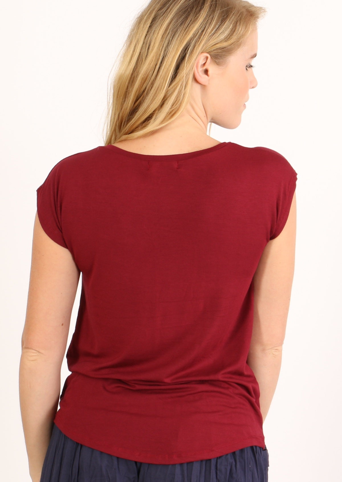 Back view of a woman wearing a maroon v-neck short cap sleeve rayon top