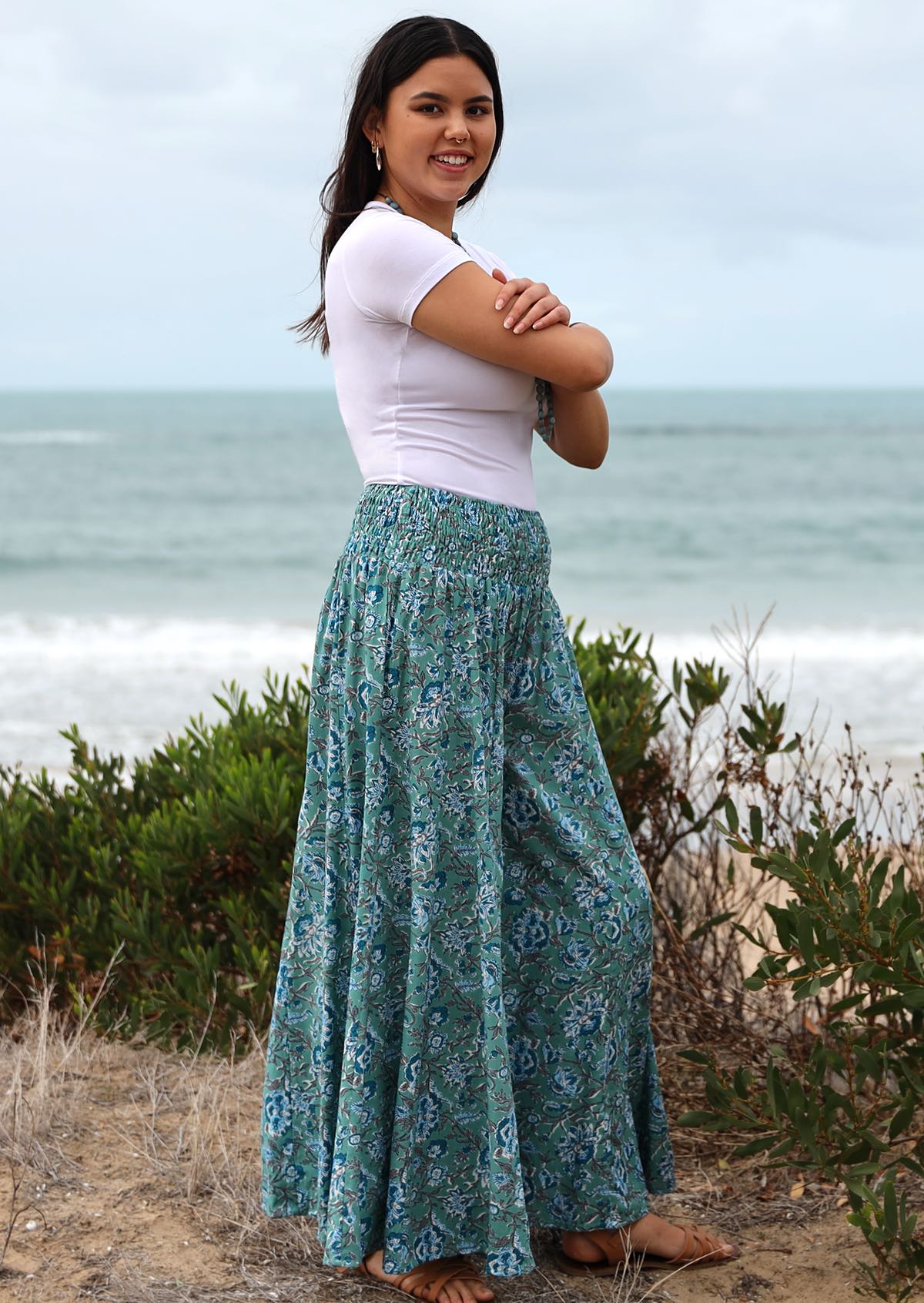 Model standing sideways wearing a 100% rayon floral printed, super wide leg pants.