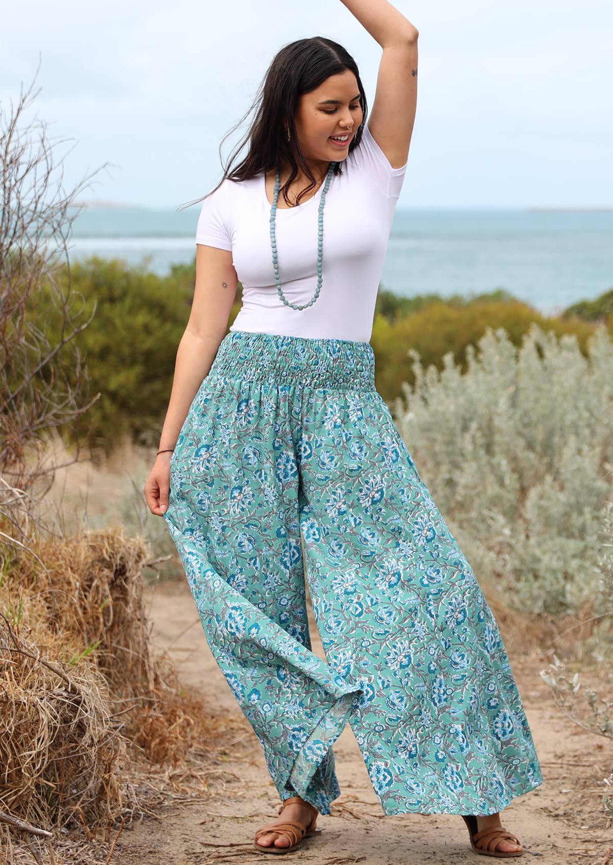 Model holding pant wears rayon wide legged womens palazzo pant with elastic waist