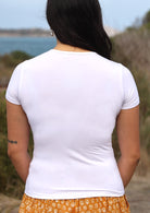 Back view of woman wearing a scoop neck white rayon fitted t-shirt.