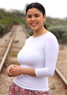 Woman wearing a rayon boat neck white 3/4 sleeve top.