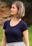 Woman with a light brown bob wearing a scoop neck navy blue rayon fitted t-shirt.