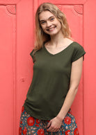 Woman wearing a olive green v-neck short cap sleeve rayon top