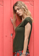 Side view of a woman wearing a olive green v-neck short cap sleeve rayon top