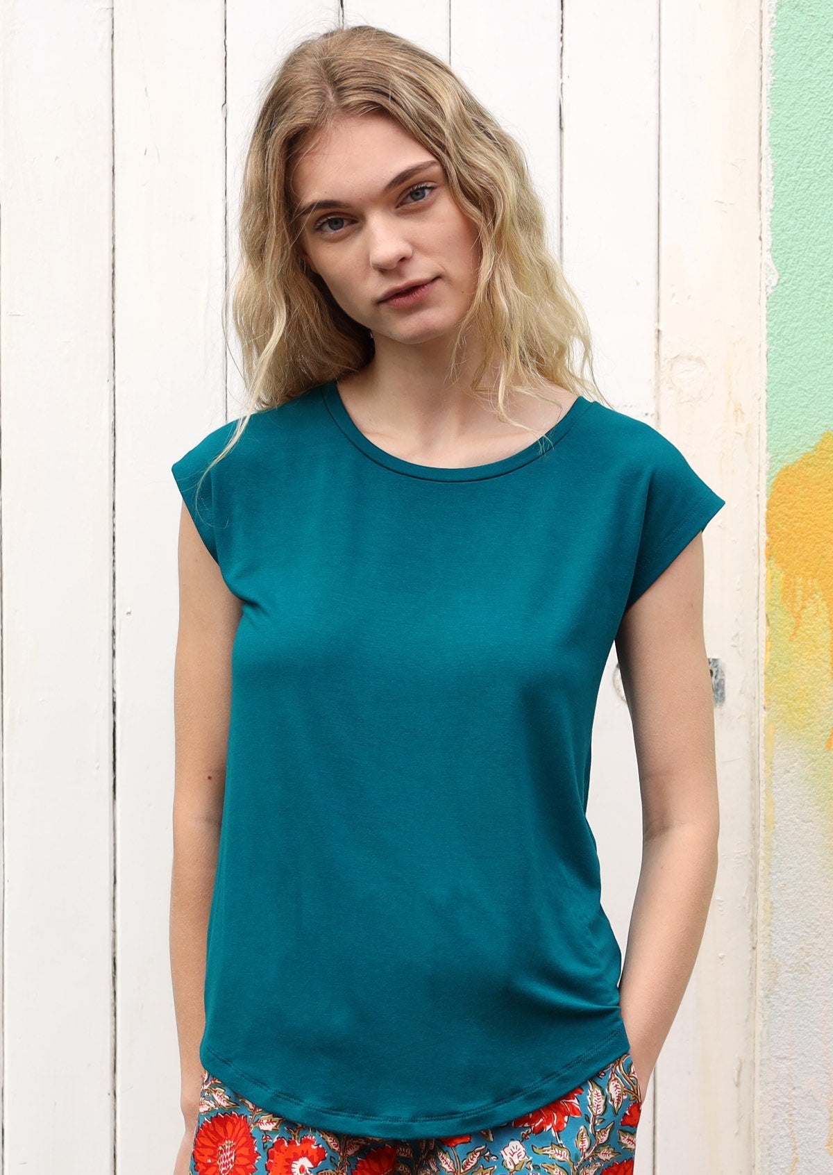 Woman wearing a soft flattering fit teal rayon jersey t-shirt with red pants.