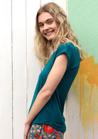 Side view of a woman wearing a soft flattering fit teal rayon jersey t-shirt.