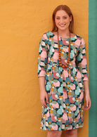 Model wears cotton dress with wide rounded neckline, 3/4 sleeve, knee length and pockets in pastel print