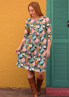 Women wear pastel print cotton knee length dress with 3/4 sleeves and wide round neckline, paired with tan boots