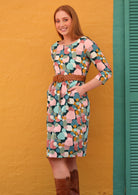 Model wears fun pastel printed cotton women's knee length dress with pockets, paired with a tan belt