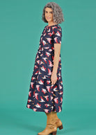 Woman wearing relaxed fit dress with blue base and pink pelican design