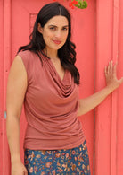 Woman wearing dusty rose rayon cowl neck top with floral skirt