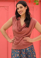 Woman with hand on her hips wearing dusty rose cowl neck top