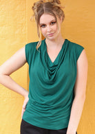 Woman wearing a jade green cowl neck rayon top with hand on hip.