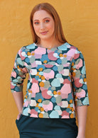 Woman wears pastel dotty print boxy top with 3/4 sleeves and a round neckline