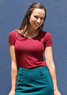 Woman wearing a scoop neck maroon rayon fitted t-shirt with green skirt.