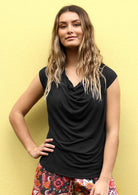 Woman wearing black cowl neck cap sleeve rayon top