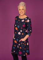Model standing with hands in pockets wearing 100% cotton dress in bold and colourful printed dress.