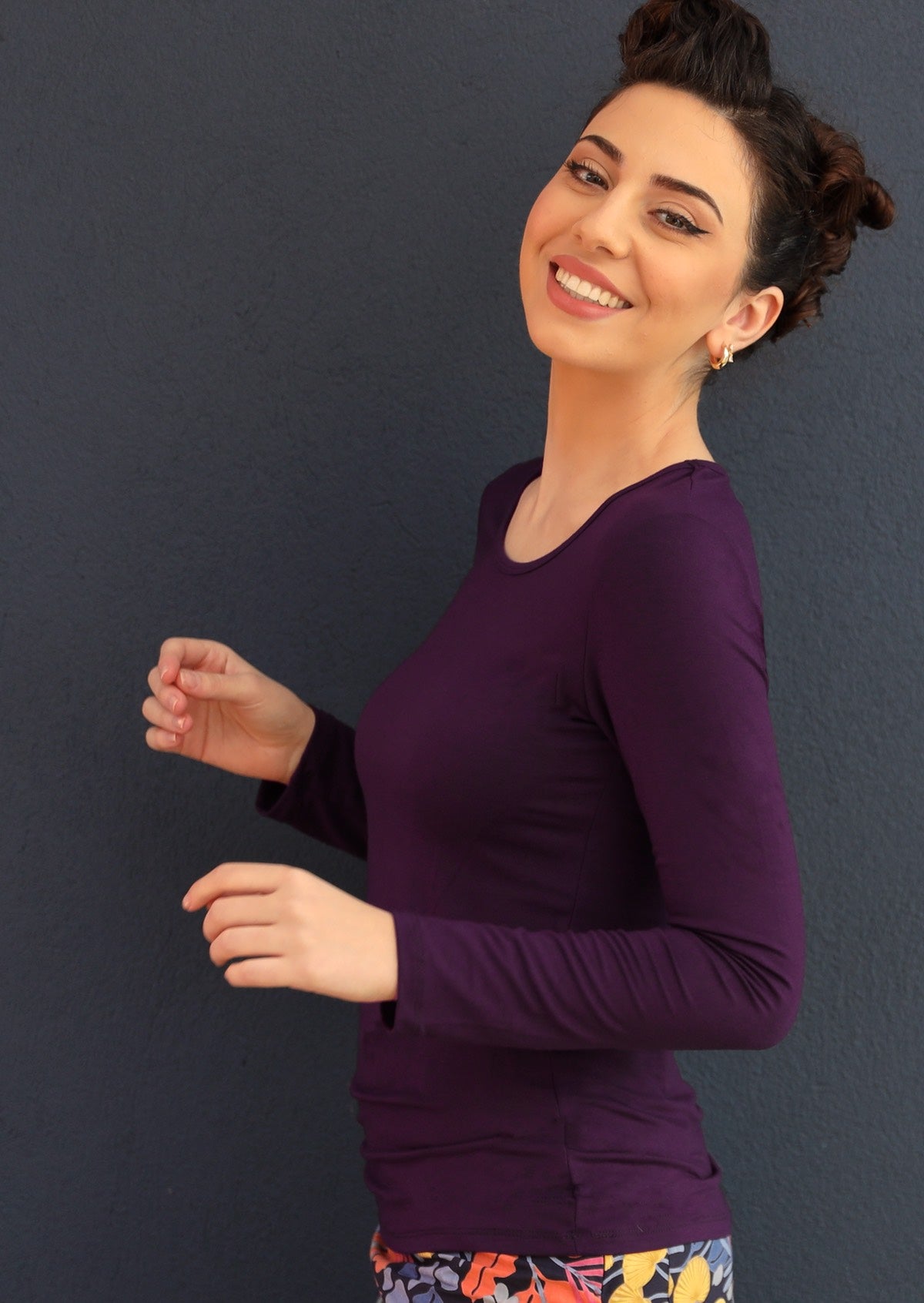 Side view of woman wearing a round neck purple long sleeve rayon top.