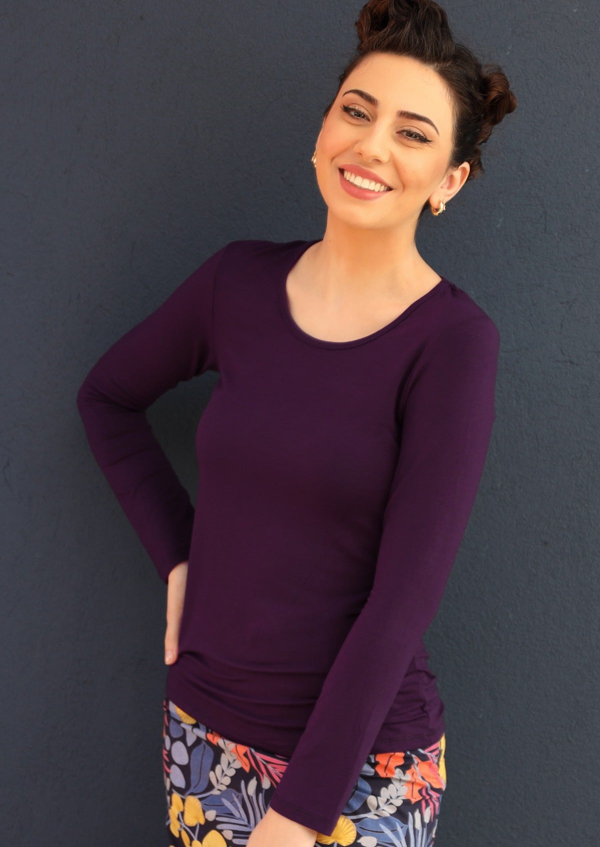 Woman with dark hair wearing a round neck purple long sleeve rayon top.