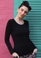Woman wearing a round neck black long sleeve rayon top in front of pink and green wall.