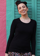 Woman with dark hair wearing a round neck black long sleeve rayon top.