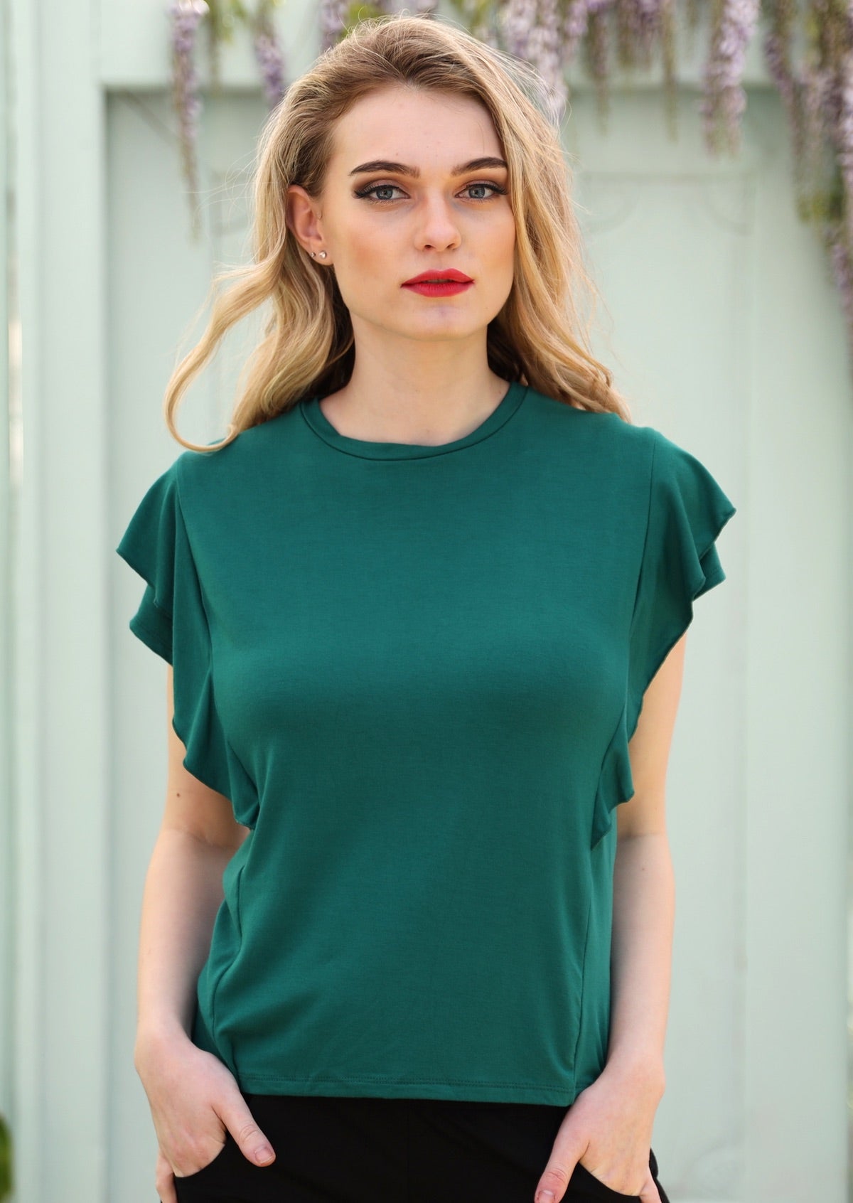 Woman wearing a ruffle green round neck short cap sleeve rayon top.