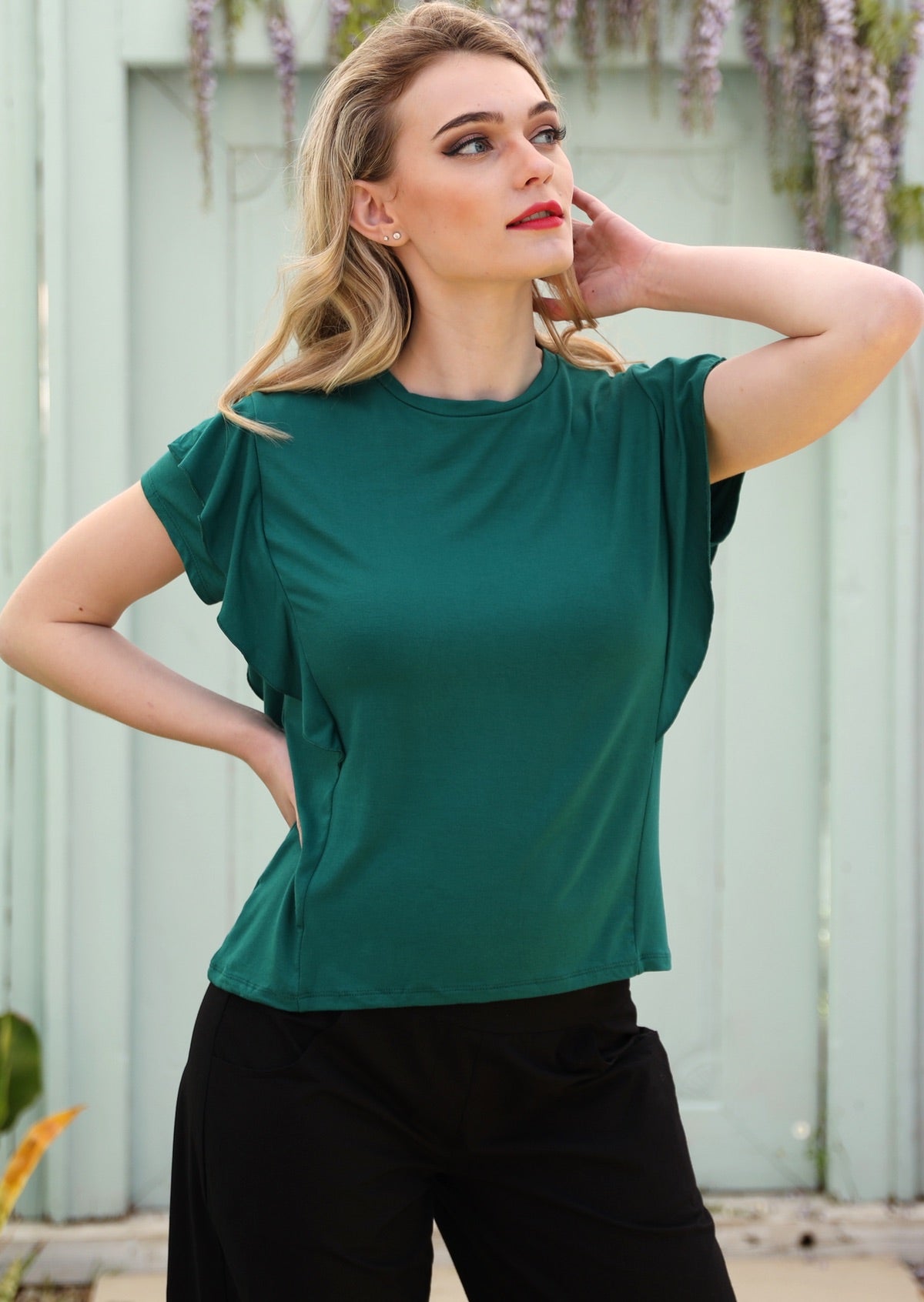 Woman with blonde hair wearing a ruffle green round neck short cap sleeve rayon top.