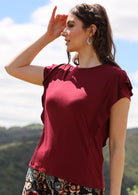 Woman wearing a maroon ruffle round neck short cap sleeve soft stretch rayon top with navy floral pants.