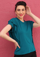 Woman with dark hair wearing a teal ruffle rayon top.