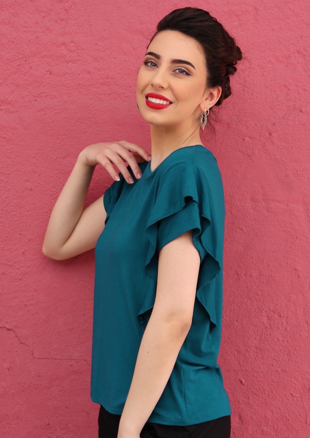 Side view of a woman wearing a teal ruffle rayon top.
