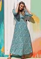 Model wears blue and white floral print rayon maxi dress with buttoned bodice and 3/4 sleeves