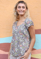 Woman wears cotton cap sleeved top with deep U-neckline in floral print with pink and lime highlights