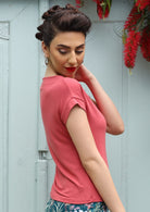 Side view woman wearing a wide neck mod pink stretch rayon boat neck top