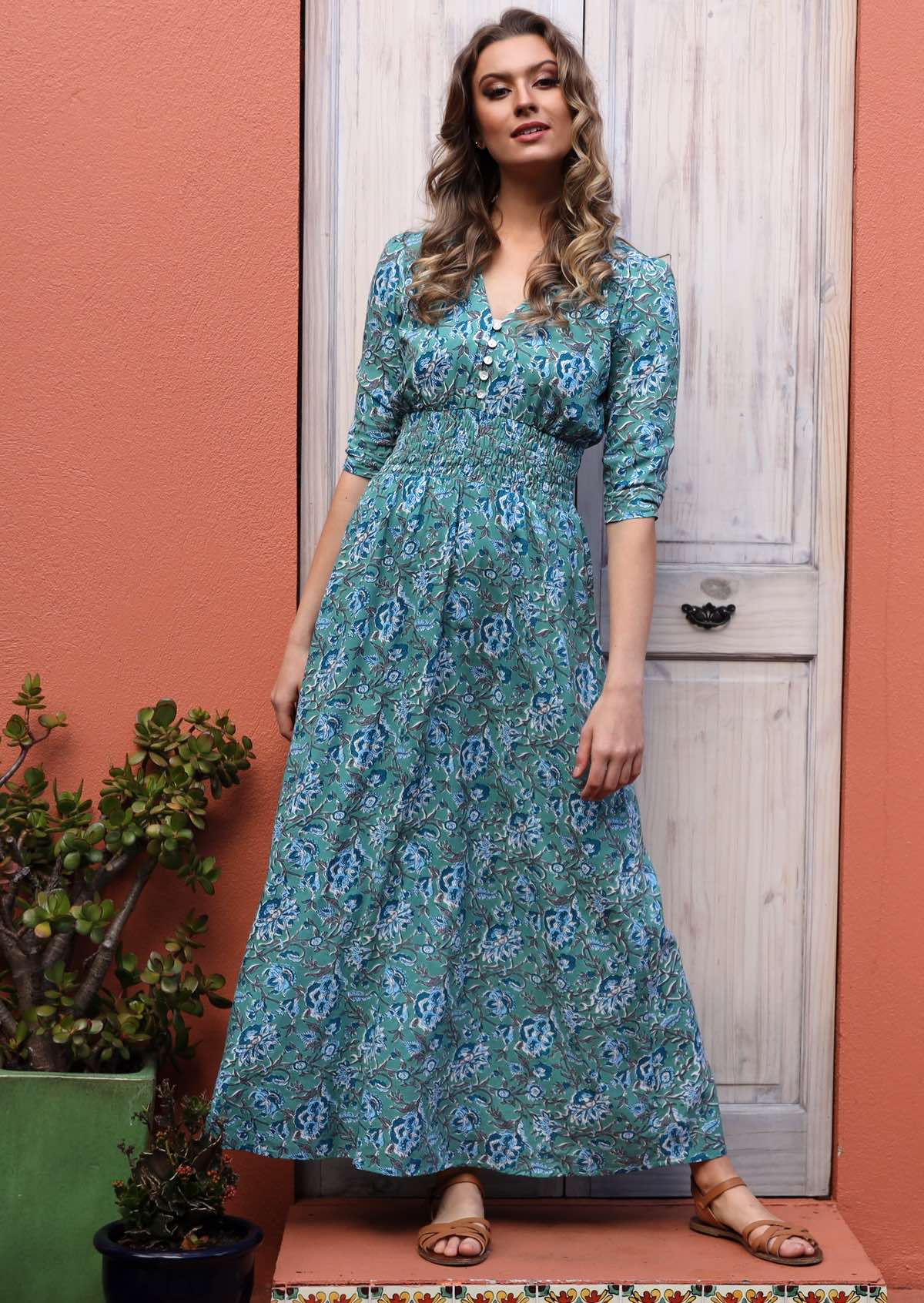 Model posing in floral maxi dress with buttoned bodice, 3/4 sleeves and V neckline